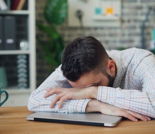 “만성피로, 일상 속 소소한 변화로 극복하기” a man sitting at a desk with his head in his hands